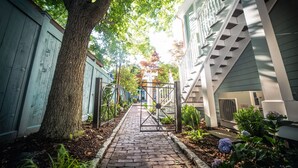 A narrow brick pathway flanked by wooden fences and a tree, leading to a gated entrance. - Town & Tide Inn (Newport)