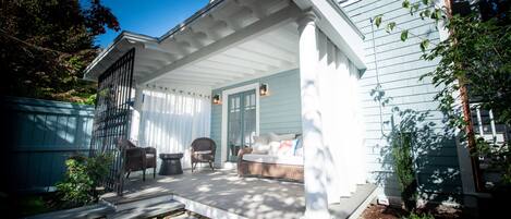 A covered porch with a bench, a chair, and a small table.