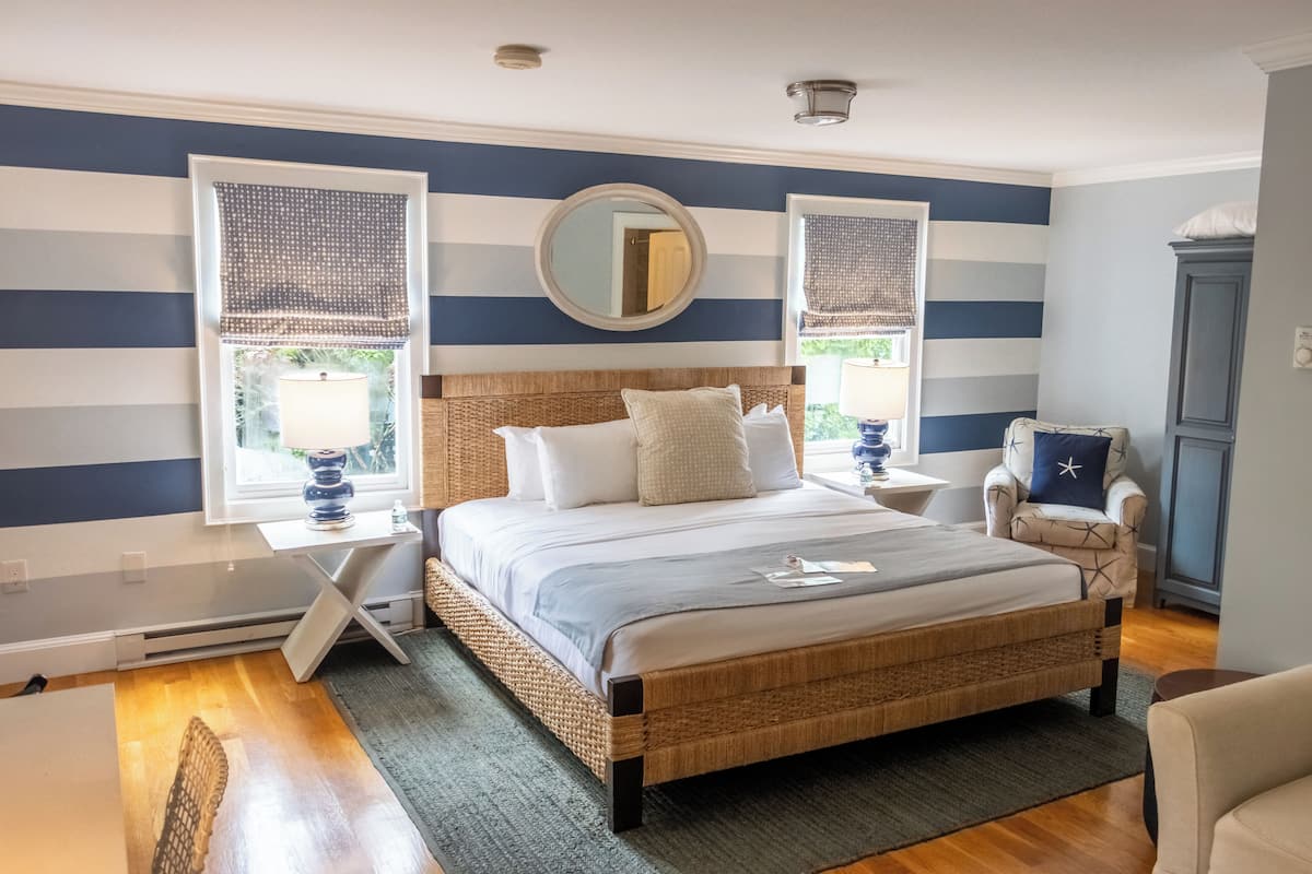 A bedroom with a bed, two bedside tables, a chair, a dresser, and a window with a view.