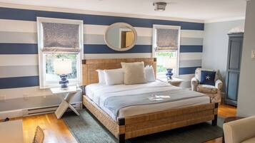 A bedroom with a bed, two bedside tables, a chair, a dresser, and a window with a view.