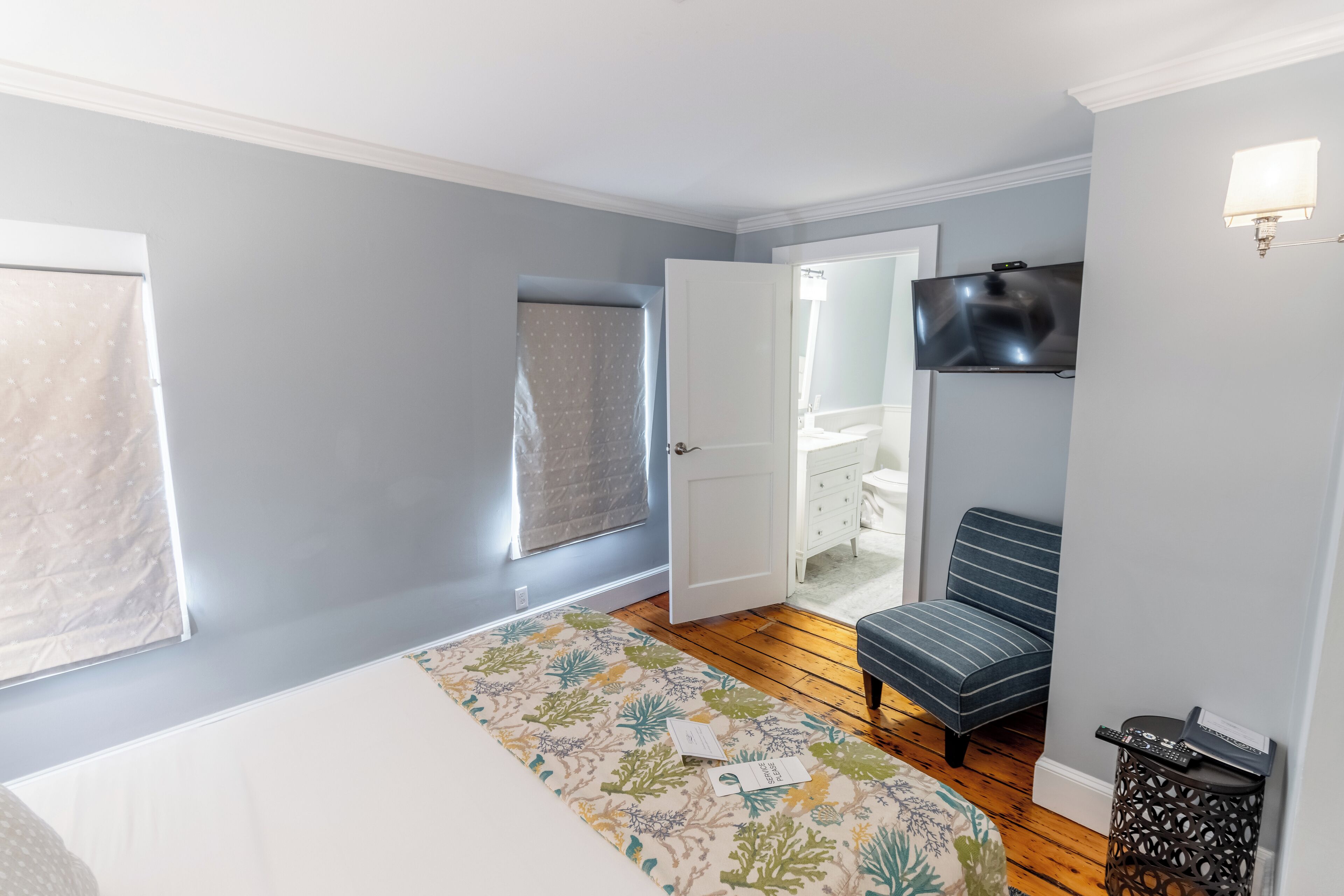 A bedroom with a bed, a chair, a TV, and a window.