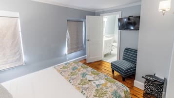 A bedroom with a bed, a chair, a TV, and a window.