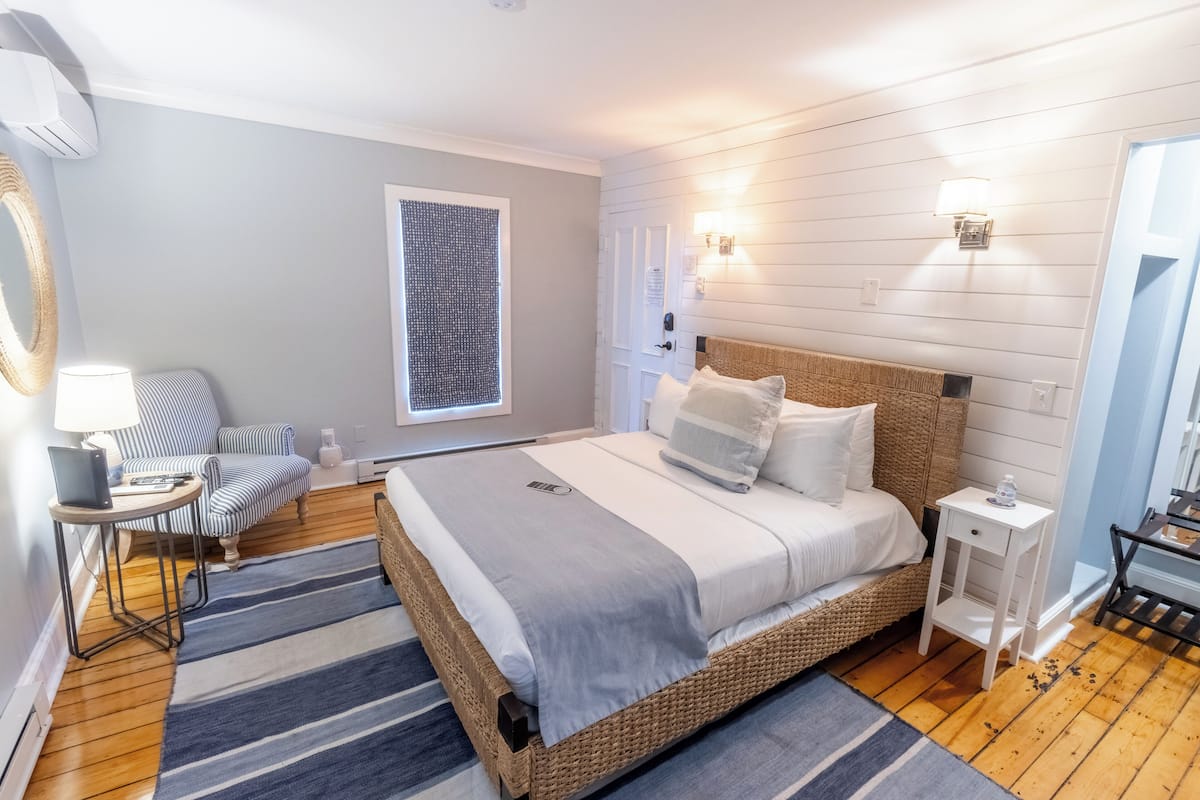 A bedroom with a large bed, a bedside table, a chair, a lamp, and a window.