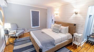 A bedroom with a large bed, a bedside table, a chair, a lamp, and a window.