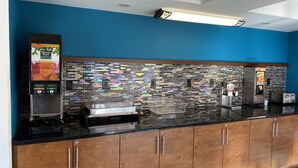 A modern kitchen with a black countertop, wooden cabinets, a tiled backsplash, and a coffee machine. - Clarion Inn Atlantic City - Beach and Boardwalk (Atlantic City)