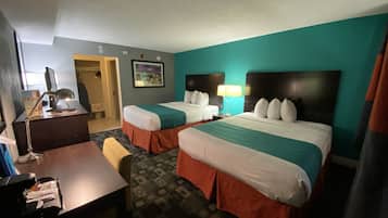 A hotel room with two beds, a desk, a chair, and a desk lamp.