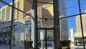 A lobby with two armchairs, a glass door entrance, and a view of the street and buildings outside. - Clarion Inn Atlantic City - Beach and Boardwalk (Atlantic City)
