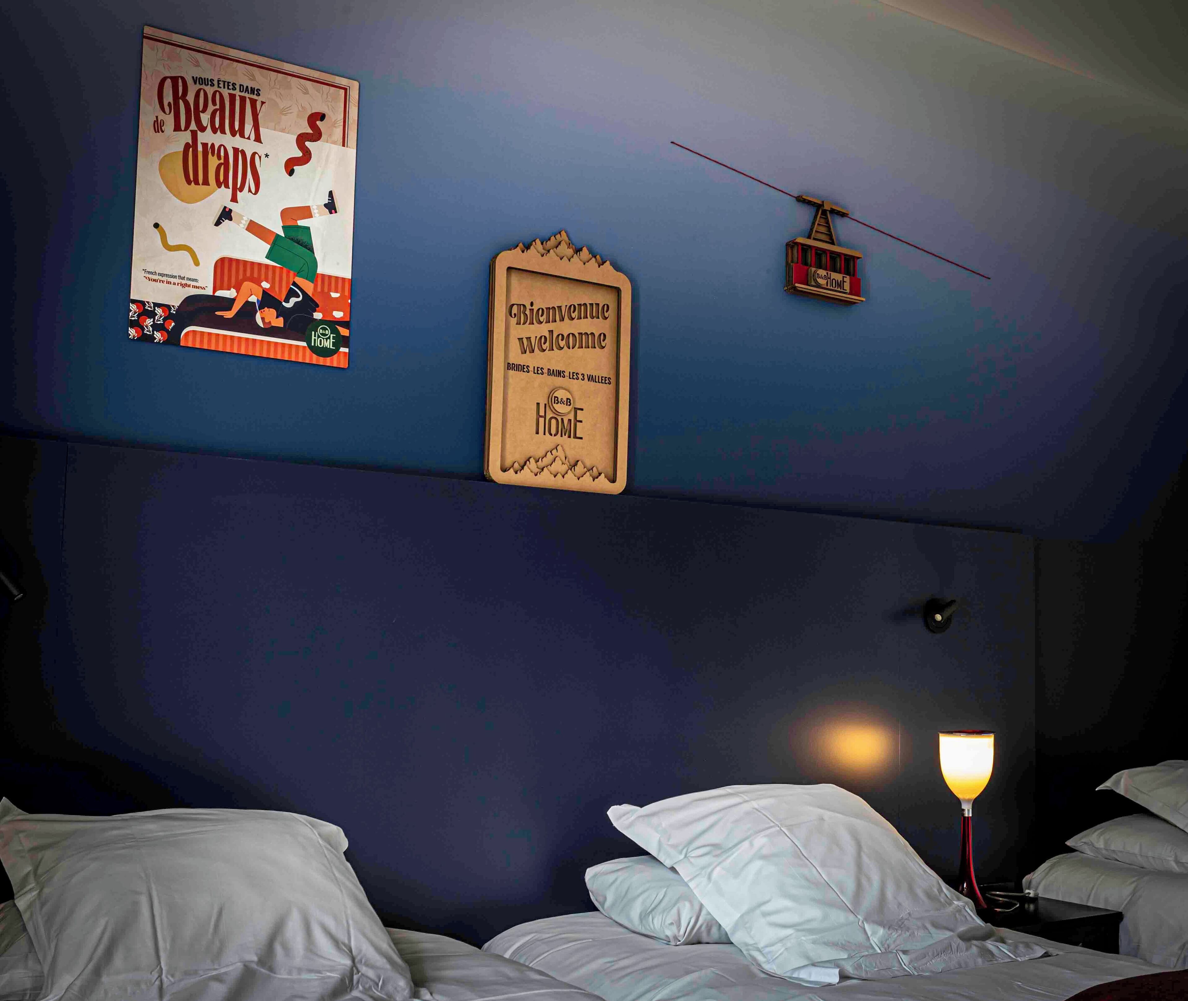 Un dormitorio con dos camas, un letrero en la pared y una lámpara colgante.