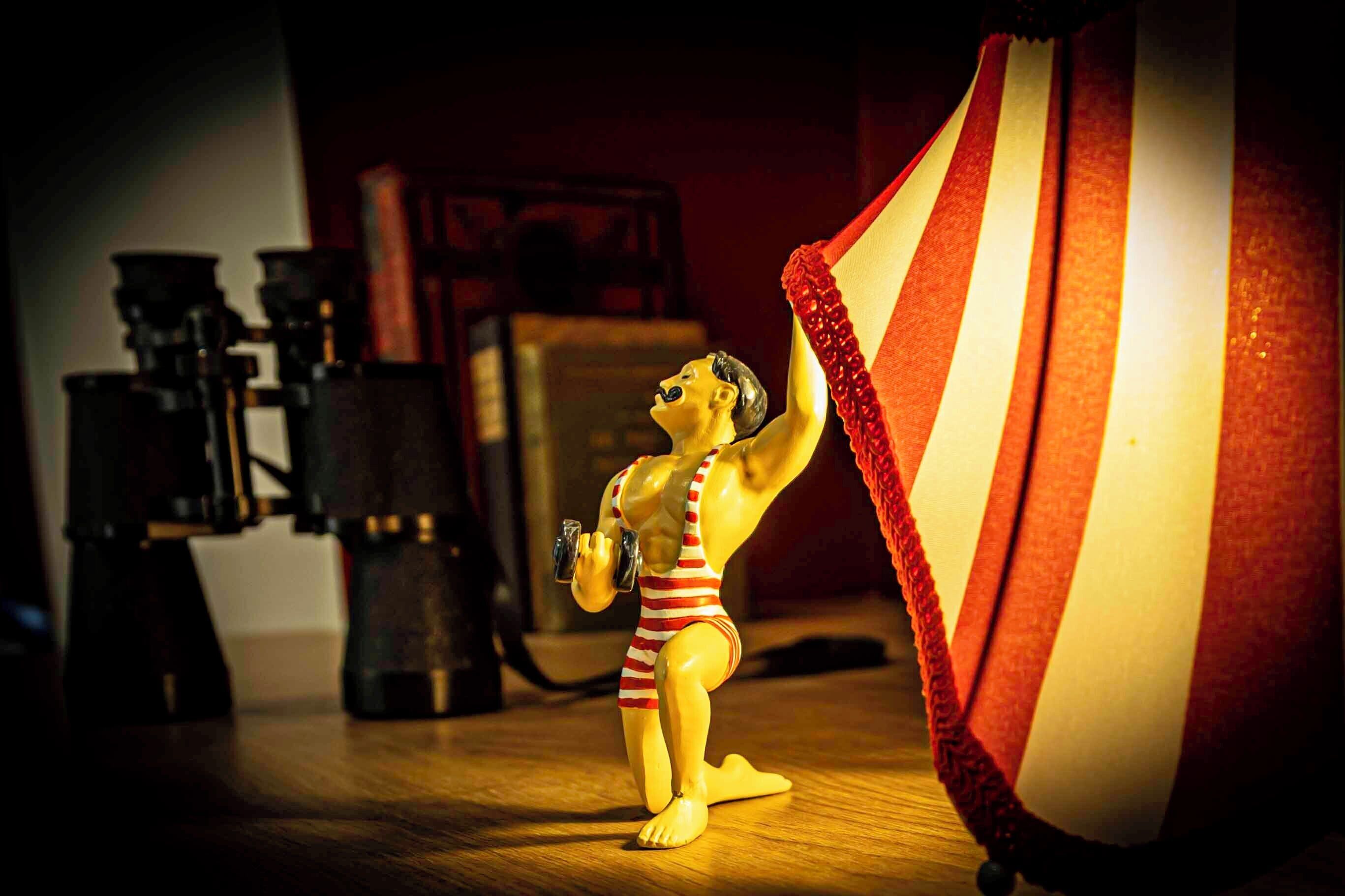 A toy figure in a striped swimsuit holding a dumbbell.