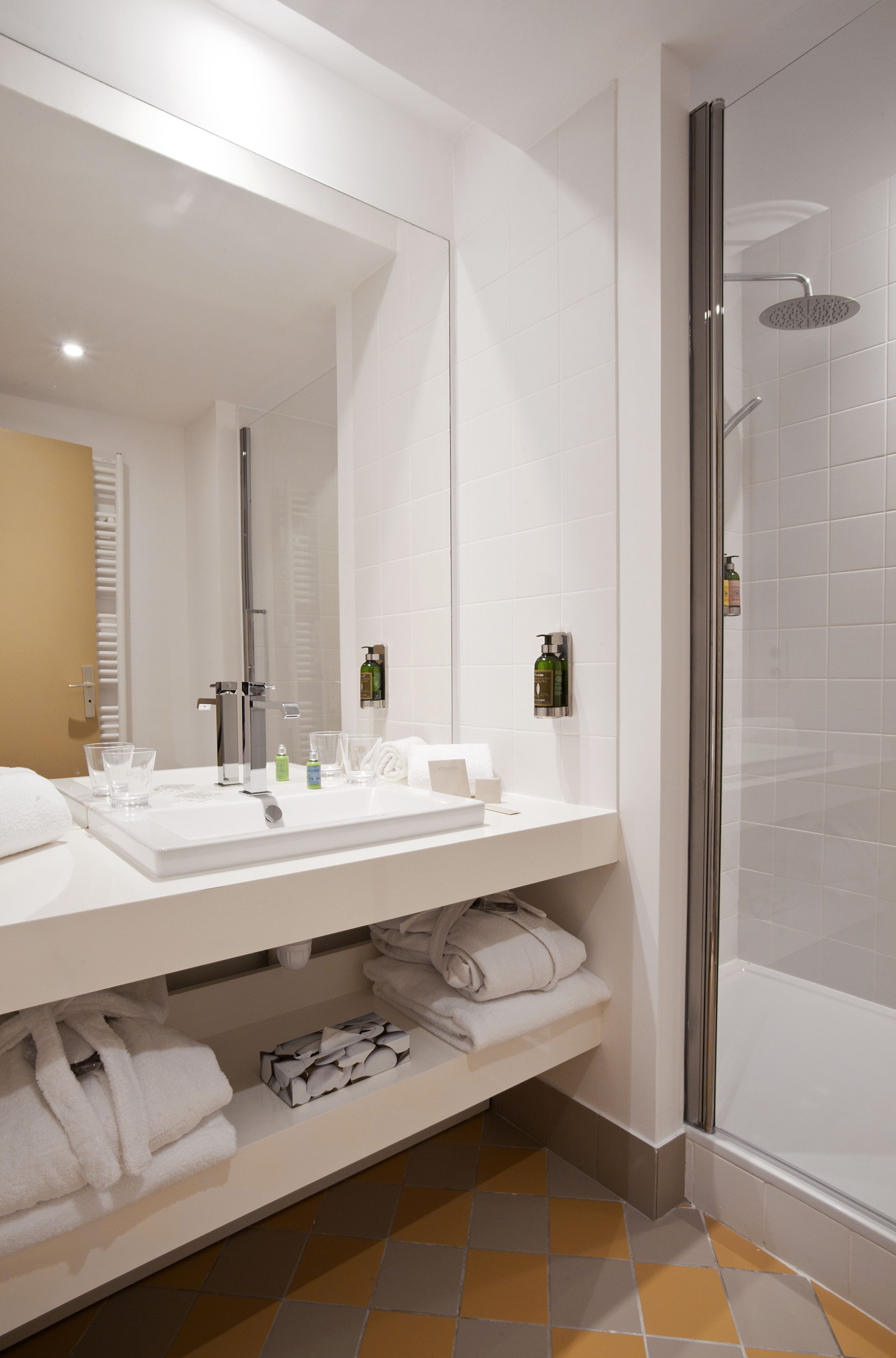 Un baño moderno con un espejo grande, lavamanos blanco y cabina de ducha con paredes de vidrio.