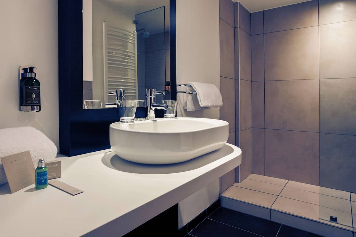 Un baño moderno con un espejo grande, un lavabo blanco y una zona de ducha.
