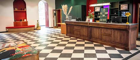 A lobby with a checkered floor, wooden reception desk, and bookshelves.