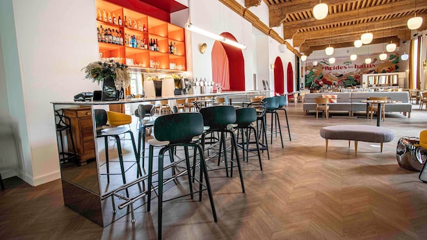 Una zona de bar con taburetes altos, una barra y un espejo.