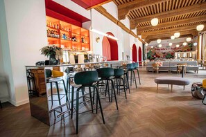 A bar area with high stools, a counter, and a mirrored wall. - B&B HOME Brides-Les-Bains Les 3 Vallées (Brides-les-Bains)