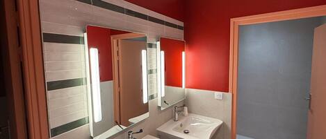 A bathroom with two sinks, a mirror, and a red wall.