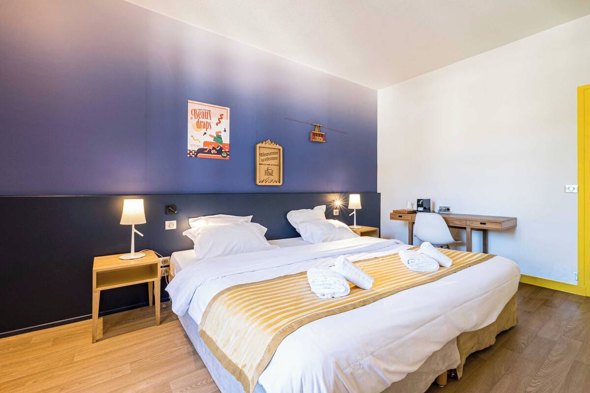 Una habitación de hotel con una cama grande, mesitas de noche con lámparas, un escritorio y una silla.