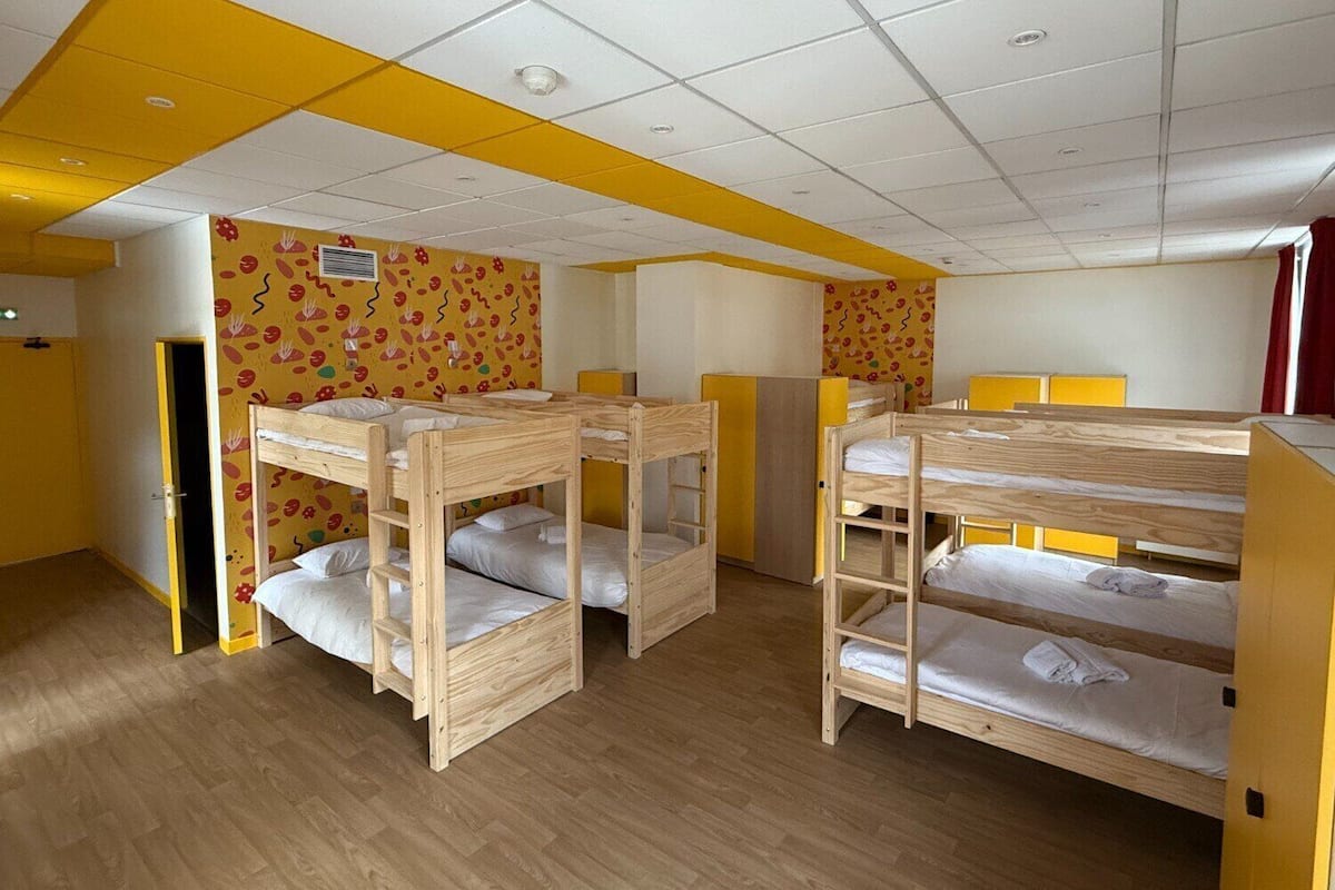 Un dormitorio con literas, pisos de madera y detalles amarillos en el techo y las paredes.