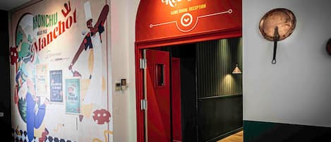 A reception area with a red door and a wall mural depicting a chef.