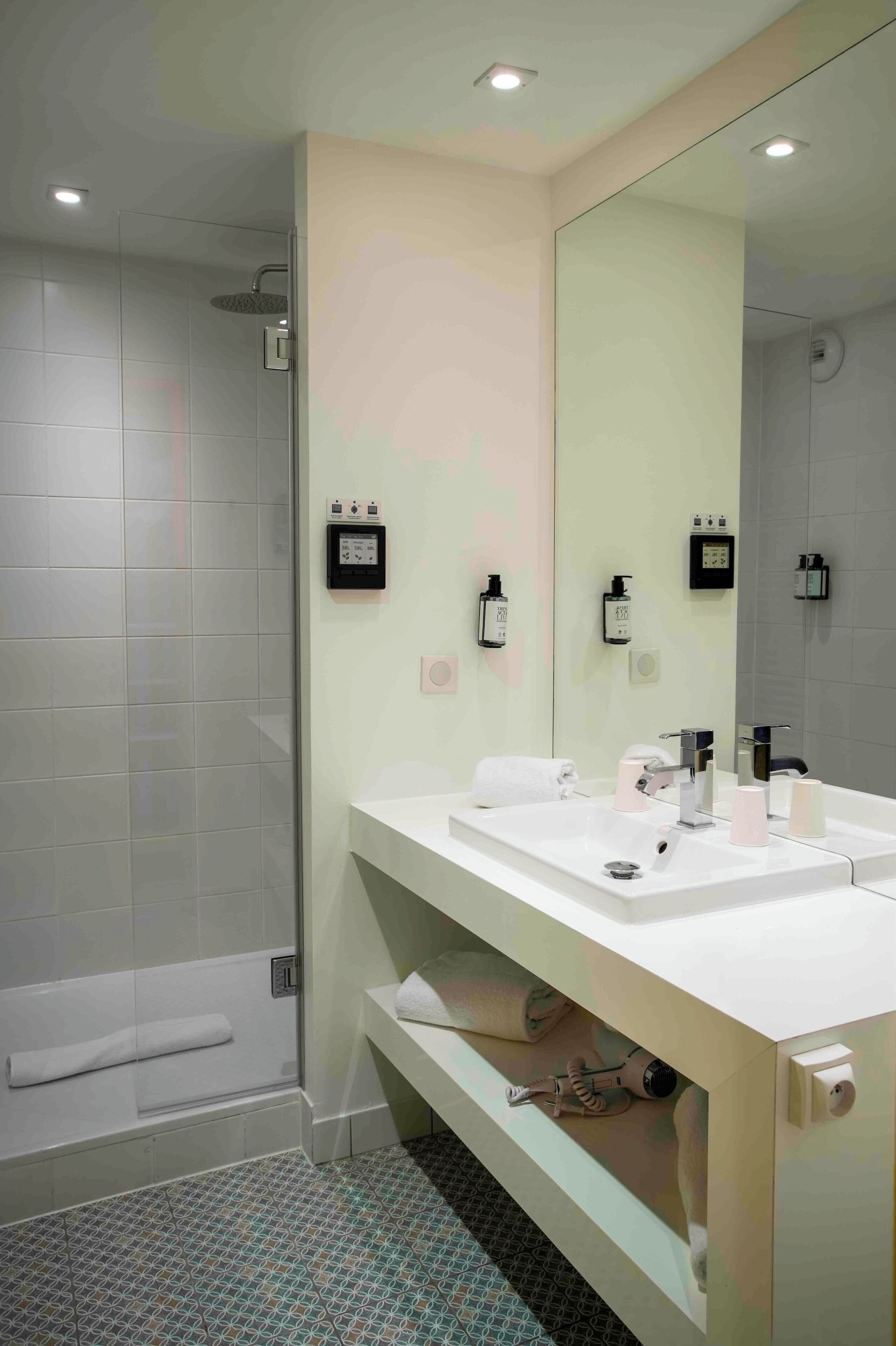Un baño moderno con ducha, un espejo grande y un tocador con lavamanos y perchero para toallas.