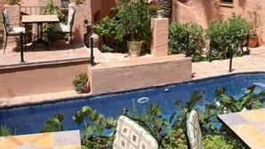 A building with a tiled roof, a palm tree, and a swimming pool. - Amanhavis Hotel (Benahavis)