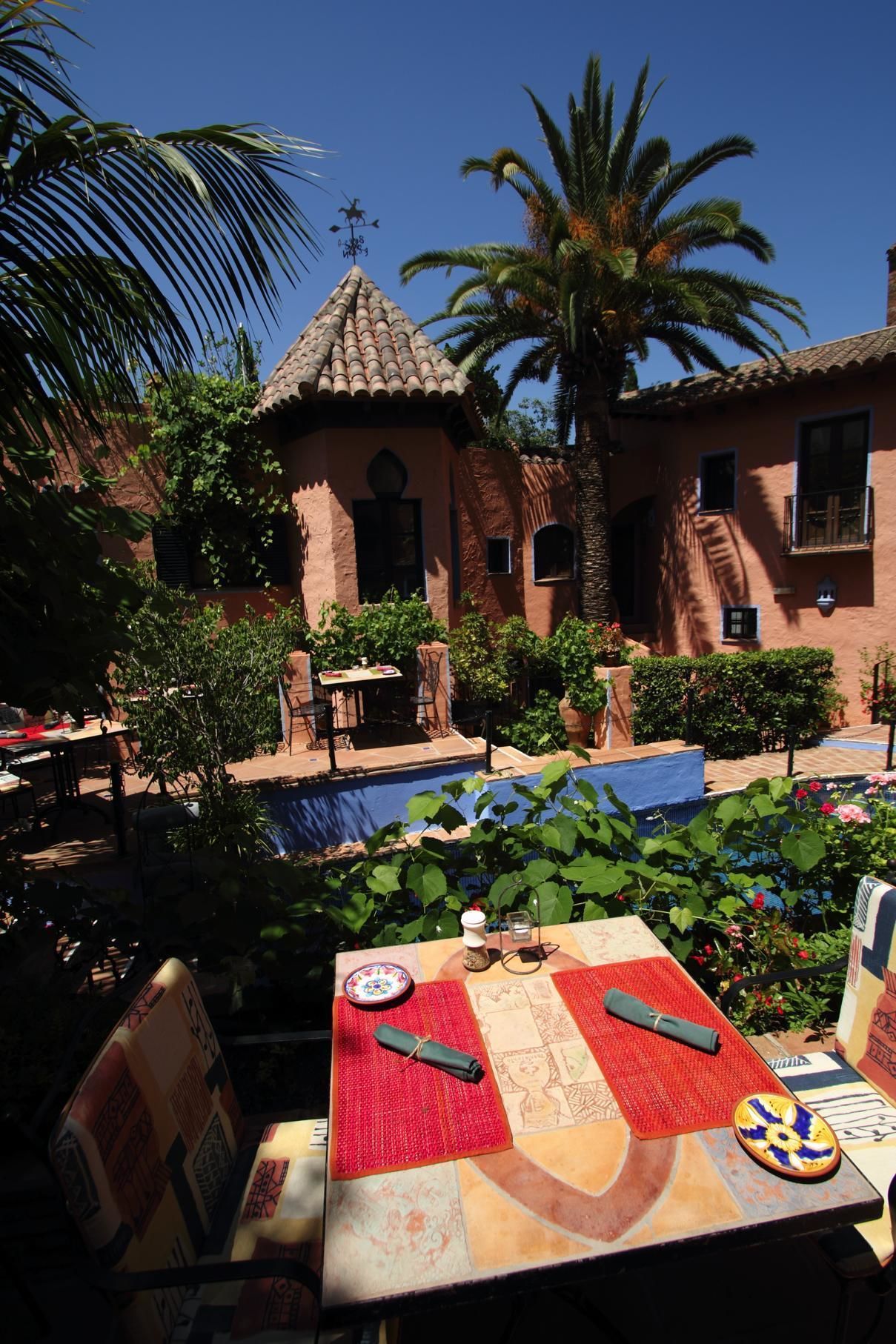 A courtyard with a pool, outdoor seating, and a building with a tiled roof.