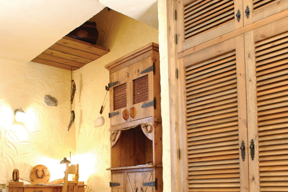 Una cocina rústica con armarios de madera, un lavabo y una zona de comedor con mesa y sillas.