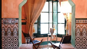 A room with a traditional Moroccan design, featuring a wooden cabinet, a table with two chairs, and a decorative archway. - Amanhavis Hotel (Benahavis)