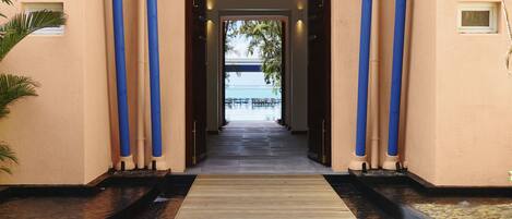 A building entrance with a blue pergola, a water feature, and a view of the ocean.