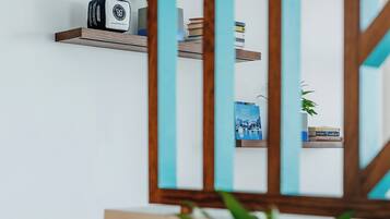 A modern interior with a wooden shelf holding books and a decorative item, a blue cabinet, and a potted plant on a wooden table.