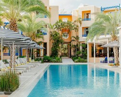 Una piscina al aire libre, sombrillas, sillones reclinables de piscina