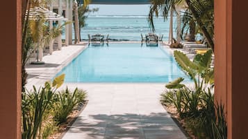 Una piscina al aire libre, sombrillas, sillones reclinables de piscina