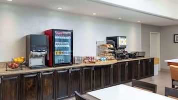 A modern kitchen area with a coffee machine, a refrigerator, and a microwave.