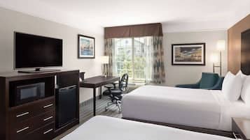 Une chambre d’hôtel avec deux lits, un bureau avec une chaise, une télévision, un four à micro-ondes et un réfrigérateur.