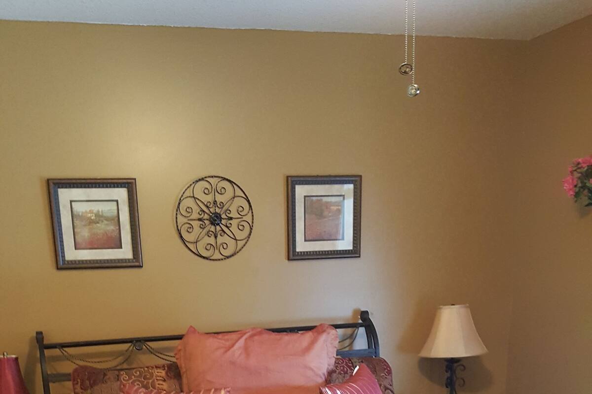 A bedroom with a bed, a nightstand, a lamp, and wall decorations.