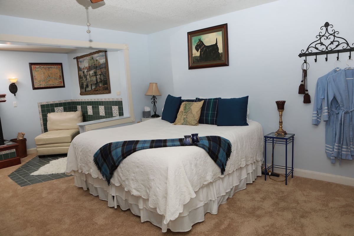 A bedroom with a large bed, a chair, a dresser, and a wall-mounted robe rack.