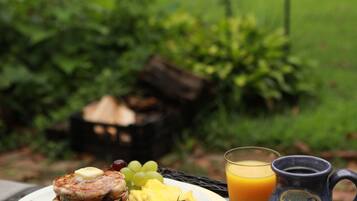 A breakfast setting with pancakes, bacon, fruit, and a mug on a table.