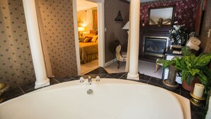 A bathroom with a large bathtub, a mirror, and a fireplace. - Woodstock Inn B&B (Independence)