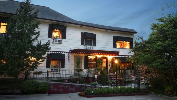 A two-story building with a porch, steps, and a brick wall. - Woodstock Inn B&B (Independence)