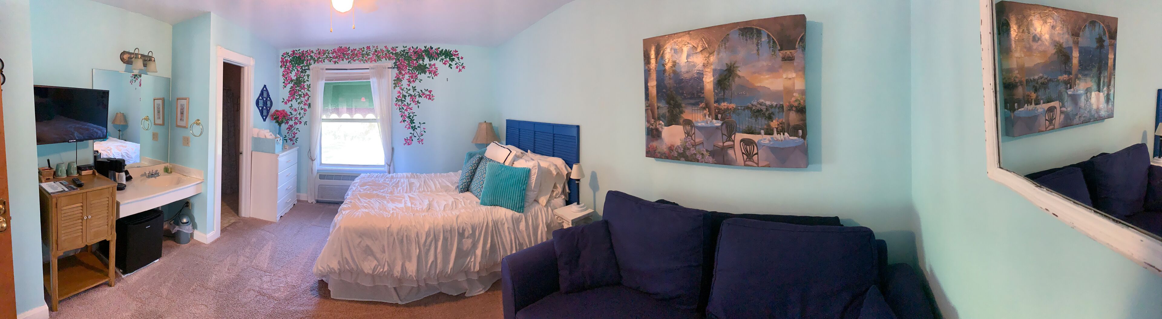 A bedroom with a bed, a TV, a desk, and a couch.