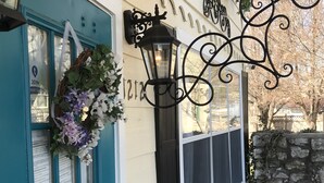 A building entrance with a blue door, a black wall-mounted lantern, and a potted plant. - Woodstock Inn B&B (Independence)