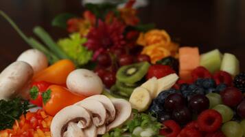 Uma travessa com uma variedade de frutas e legumes, incluindo pimentões, kiwi, uvas e cogumelos.