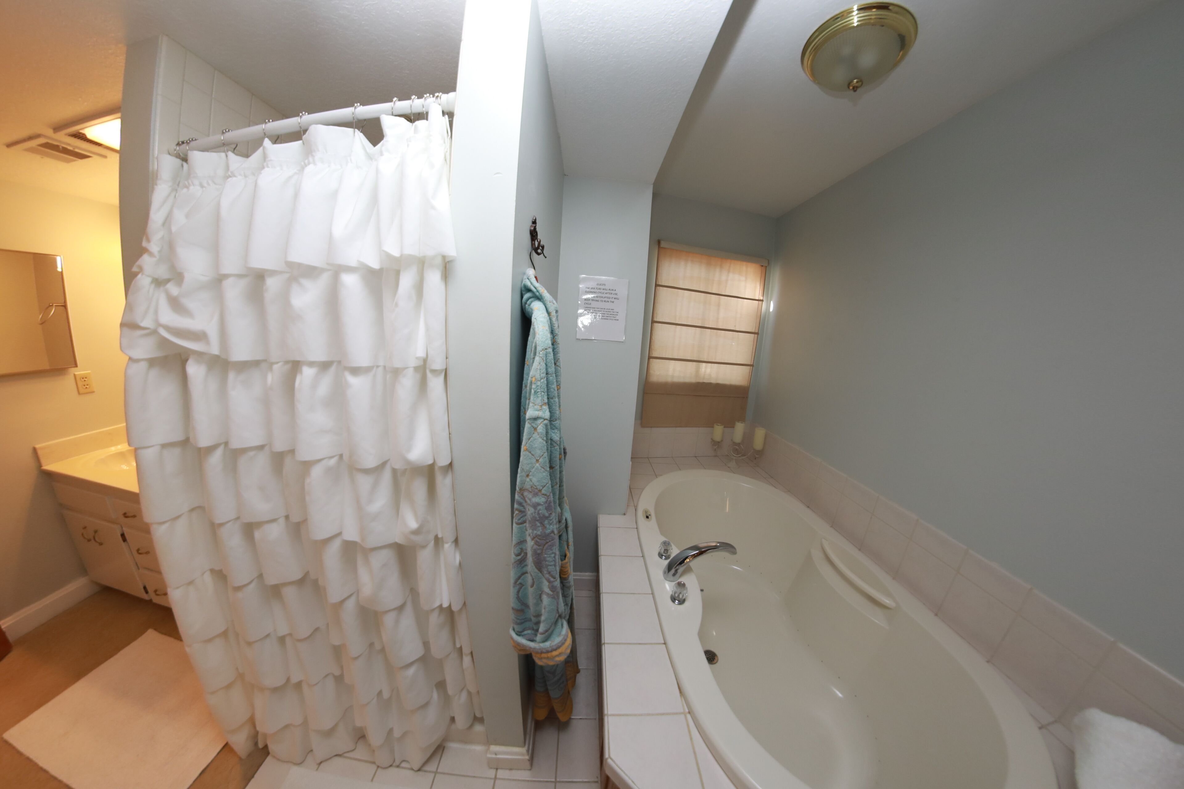Un bagno con una vasca, una tenda da doccia, un portascopino e un lavandino.