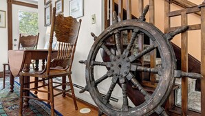 Une chaise en bois, une grande roue de navire et un escalier avec des rampes en bois.