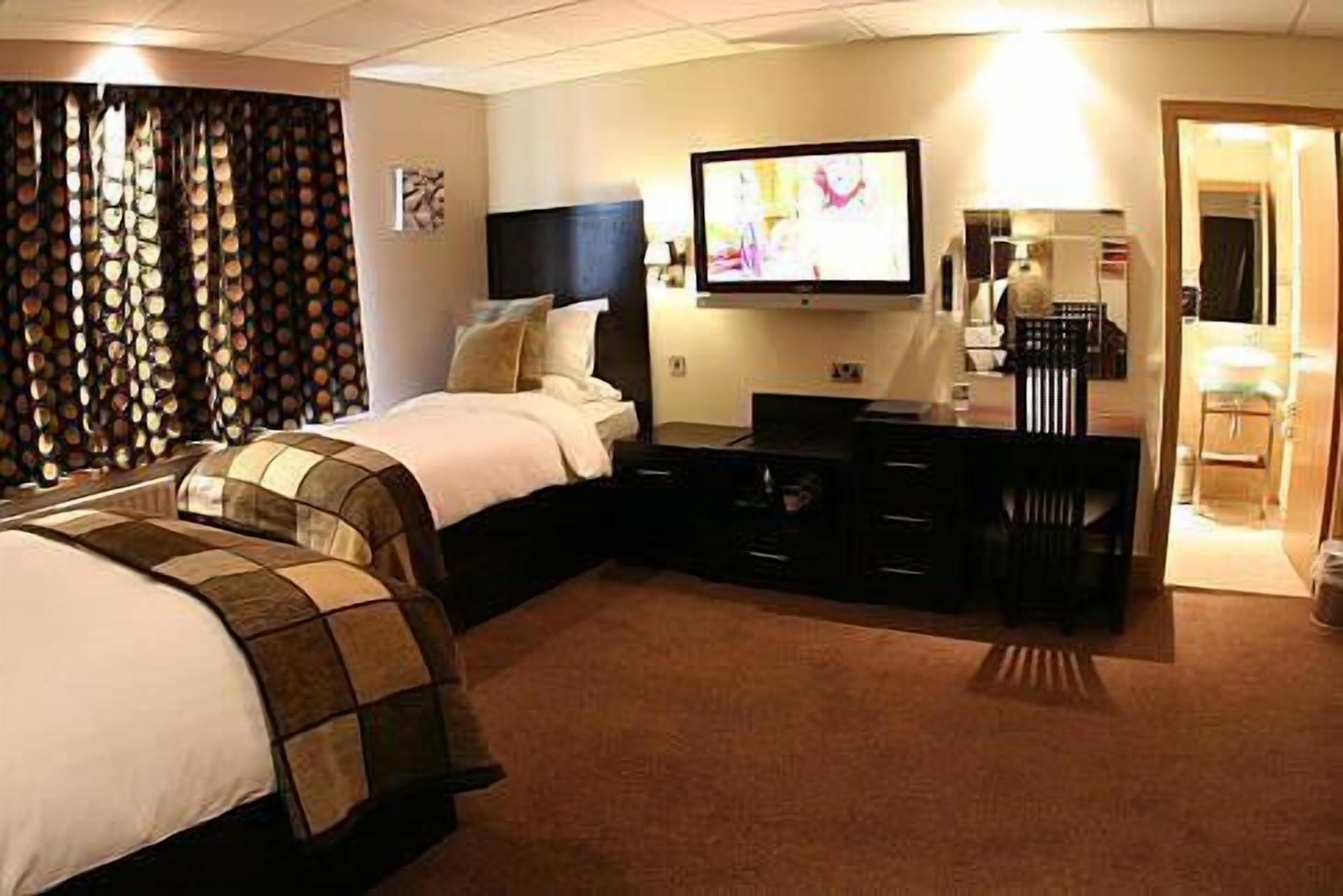 Una habitación de hotel con cama, televisión, escritorio y una silla.