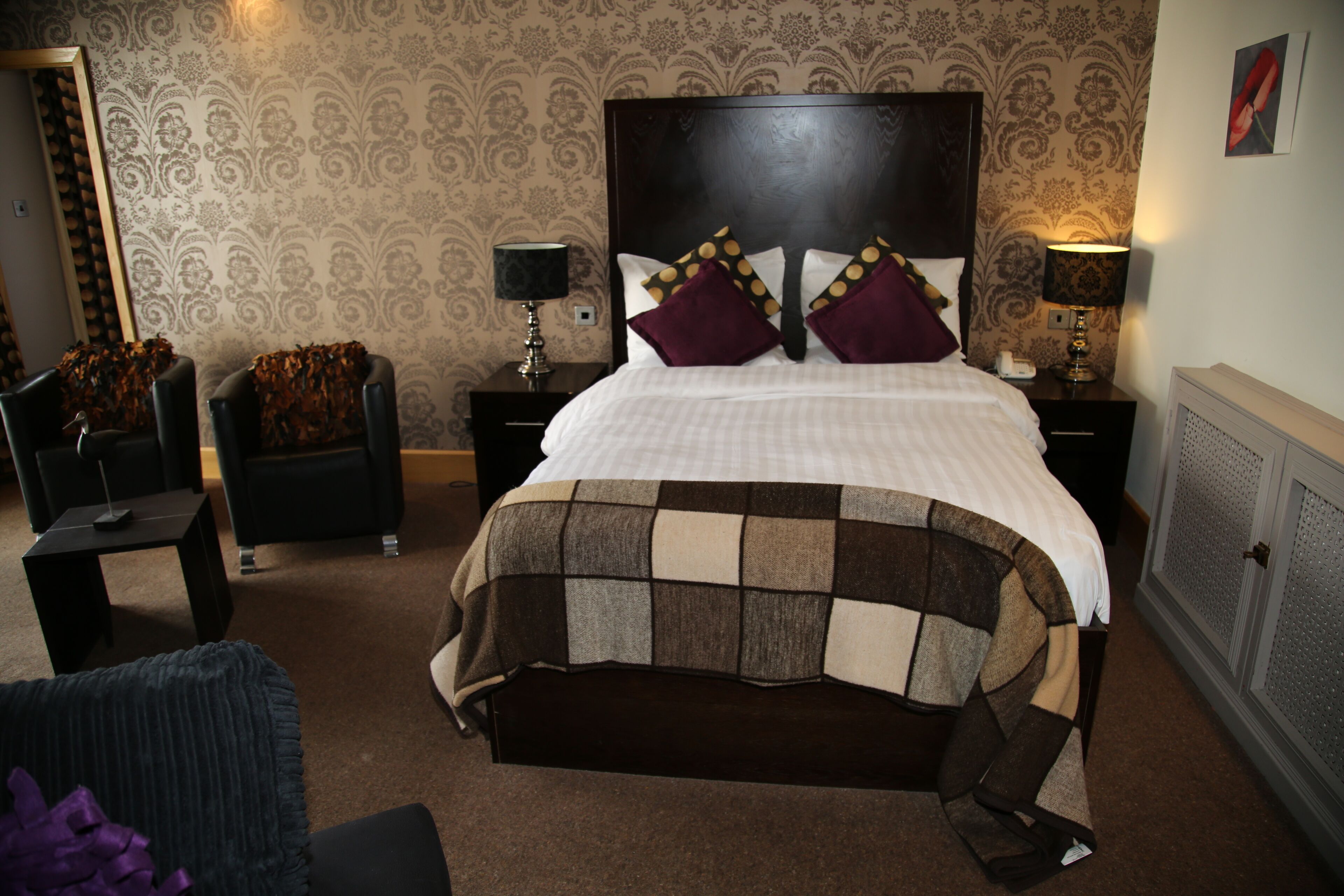 Une chambre bien rangée, avec un grand lit, deux tables de chevet, une chaise et une commode.