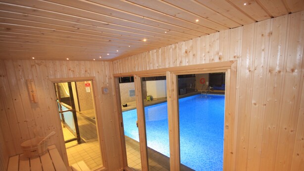 Un intérieur en bois avec un espace piscine visible à travers des portes vitrées.