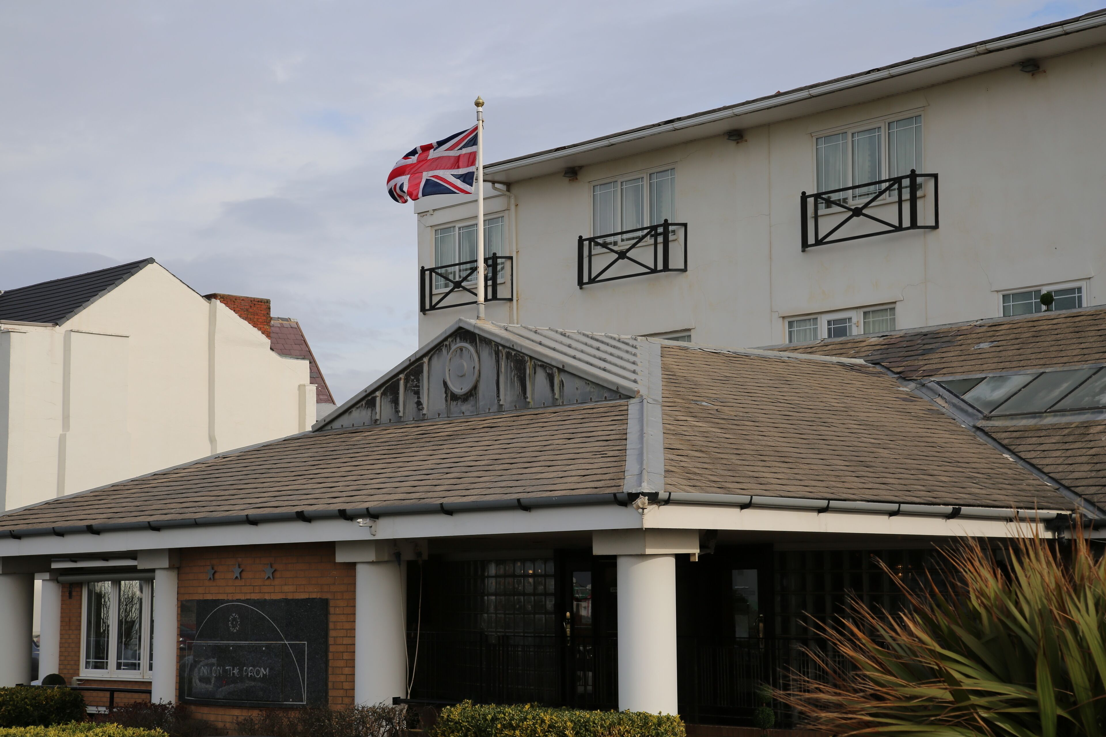 A building with a flag, a sign that reads "ON THE FROM", and a window with a black frame.