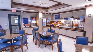 A hotel dining area with a buffet, seating arrangements, and a kitchen counter. - Holiday Inn Express and Suites Springfield Medical District by IHG (Springfield)