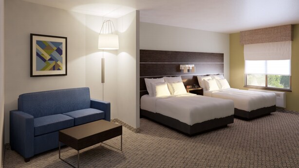 A hotel room with a blue sofa, two single beds, a nightstand, a lamp, and a framed picture on the wall. - Holiday Inn Express and Suites Springfield Medical District by IHG (Springfield)