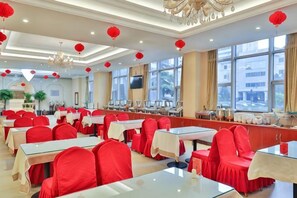 Un espace repas avec des tables et des chaises, de grandes fenêtres et des lanternes rouges.
